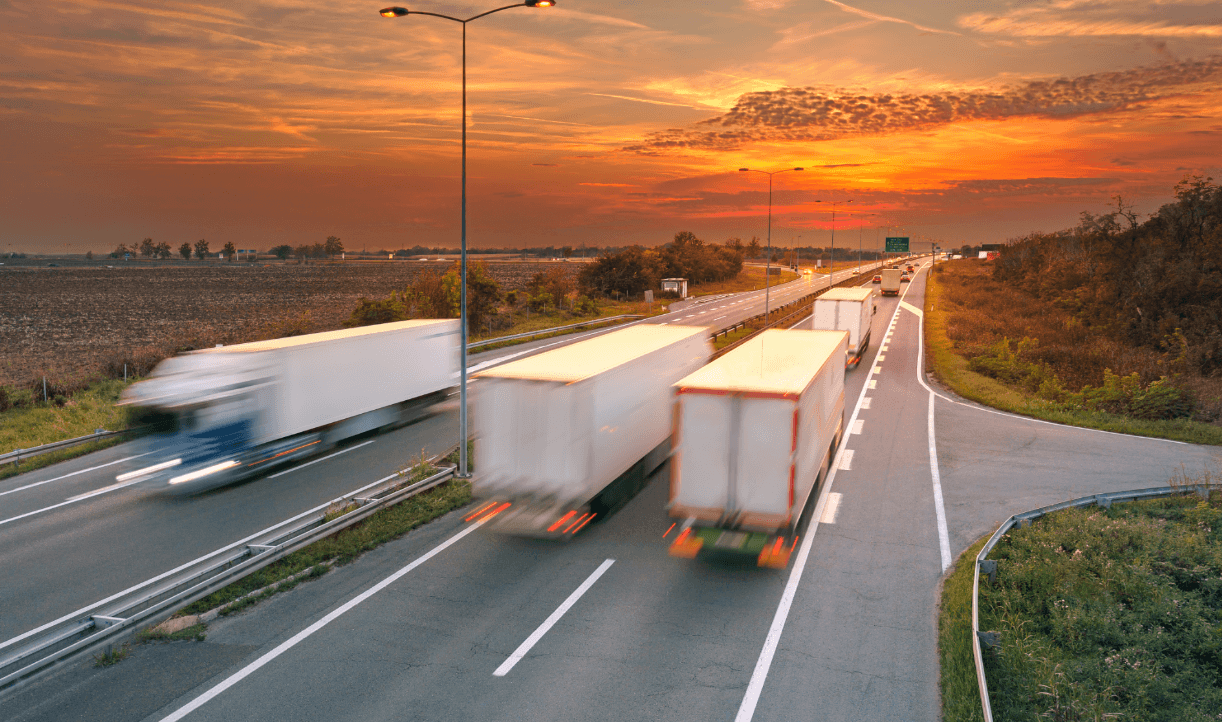 Semi trucks driving on a highway into the sunset