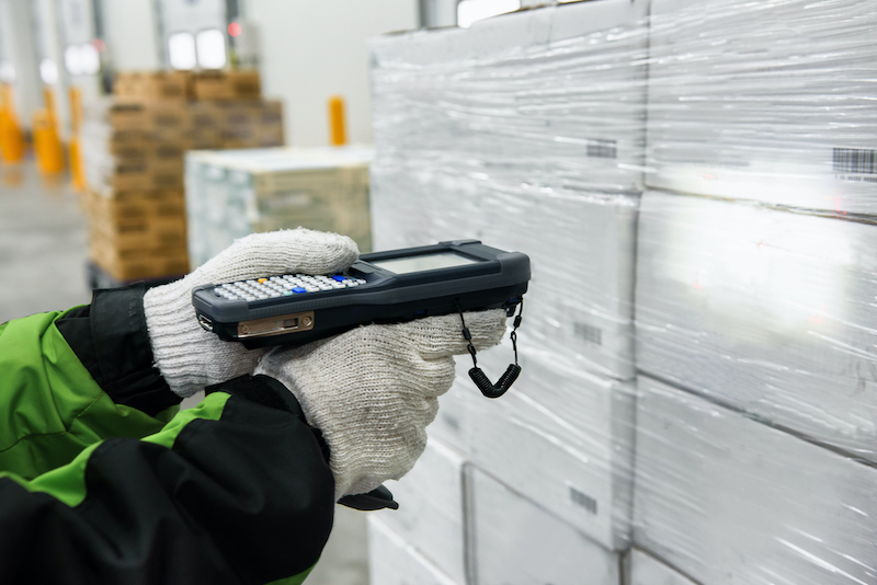 Person scanning white boxes with a barcode scanner