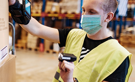 Person in safety vest scanning barcodes in a warehouse